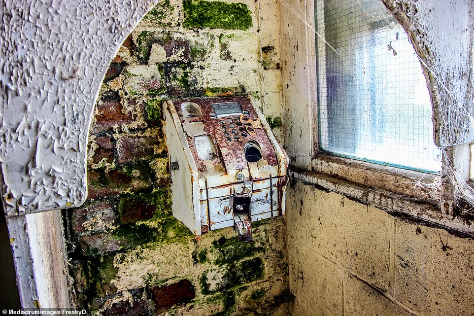 A rusty payphone appears frozen in time and is covered in rust and mould. The factory was once a thriving workplace with a rich heritage but the echoes of industry have long since faded