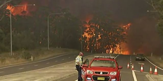 In this image made from video, officials block the Princes Highway as wildfires approach in South Coast, New South Wales Australia, Tuesday, Dec. 31, 2019.