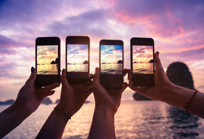 Four people taking pictures with their smartphones.