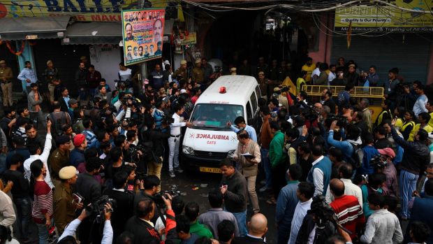 An ambulance surrounded by media drives out from a street leading to a factory site after a fire broke out in the Anaj Mandi area of New Delhi. Photograph: Sajjad Hussain/AFP/Getty Images.