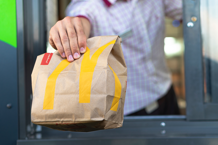 McDonald's employee hands a customer their food at the drive thru