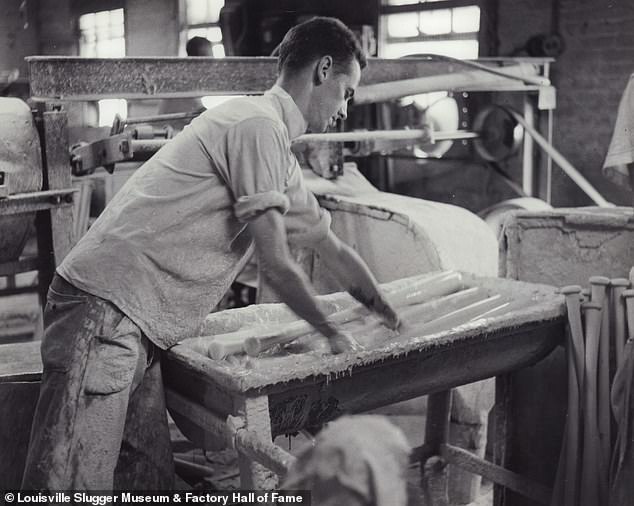 Unidentified employee applying polish to bats. Every baseball bar cores measure 37 inches long by 2.75 inches in diameter, these raw wood posts are called 'billets.' Despite their uniform size, the wood can vary in weight which is what distinguishes different models