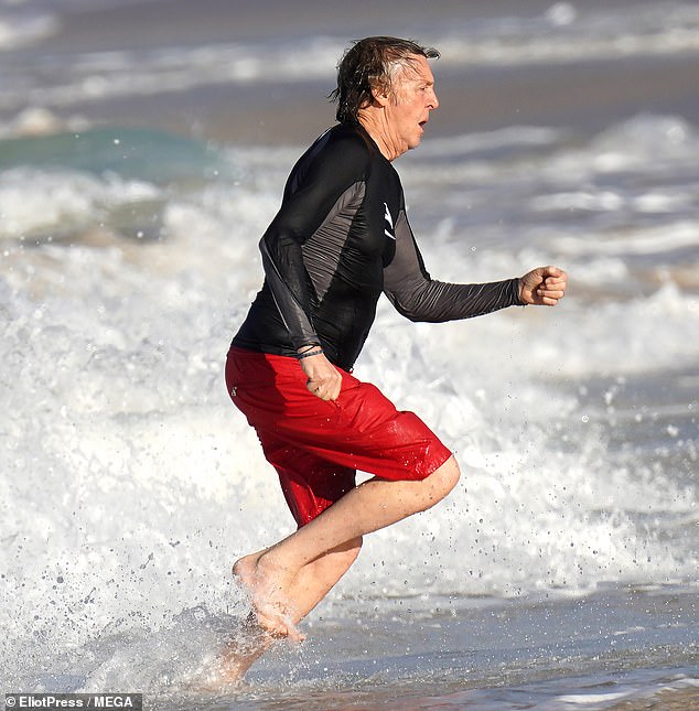 Making a splash: Paul ran through the waves, sending a flurry of water out from around his feet as he made his way back on to the beach