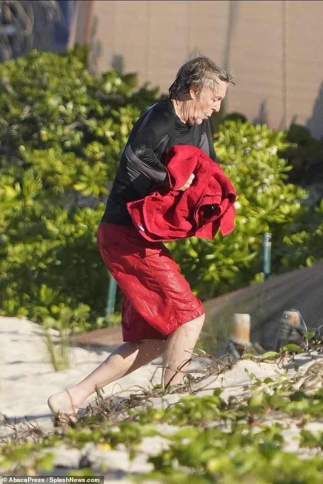 Success: Paul hugged into his red towel as he strolled along the beach