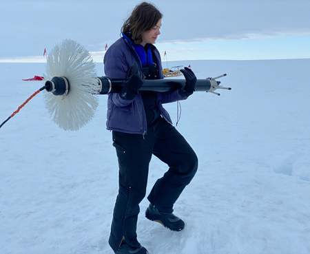 A woman carries a large device across the ice. A woman carries a large device across the ice.