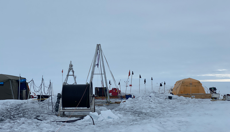 Tents, equipment, and flags against an icy backdrop Tents, equipment, and flags against an icy backdrop