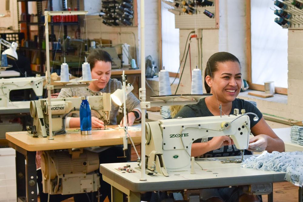 Seamstress working industrial sewing machines at Good Clothing Company in Fall River, Massachusetts. (Allison Hagan/Here & Now)