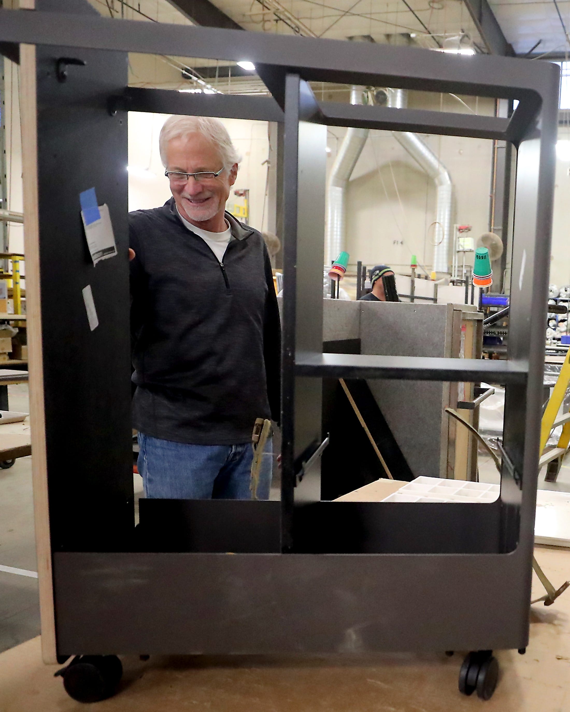 Clif McKenzie, CEO of Watson Furniture, looks over a storage cart being assembled on the factory floor in Poulsbo on Tuesday.