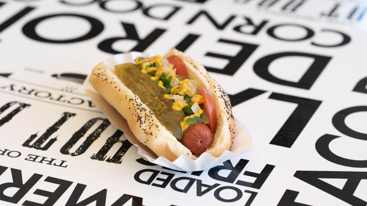 hot dog on poppy seed bun with a pickle spear