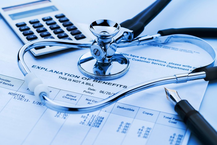 A stethoscope, pen, and calculator sitting on top of an explanation of insurance benefits form