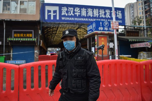 A police officer stands guard outside the now shuttered Huanan Seafood Wholesale market where the...
