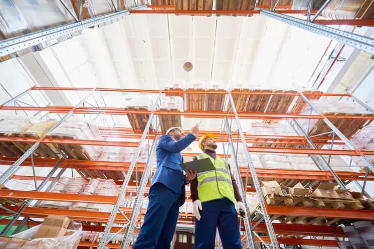 Businessman talking to warehouse worker using data from an ERP system.