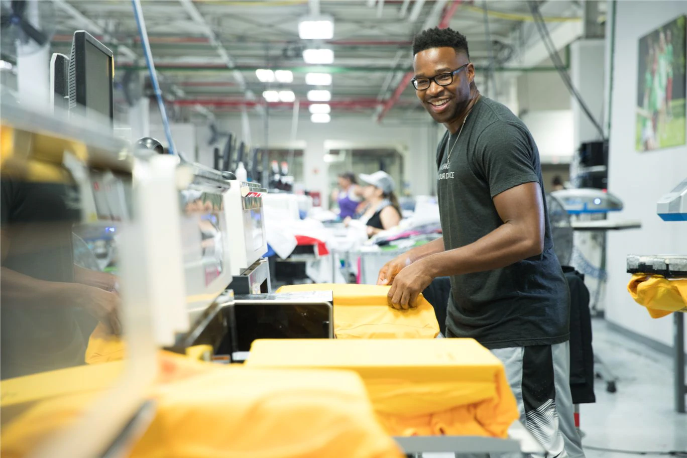 An "Inker" works the production line making T-shirts at Custom Ink.