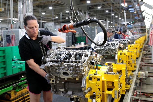 A General Motors employee working on assembling an engine at a plant in Romulus, Mich.,...