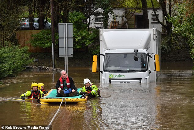 A three-man rescue team waded out to the Brakes food wholesaler lorry with a raft attached to a rope. They got the driver out of his cab through the window and brought him back to safety