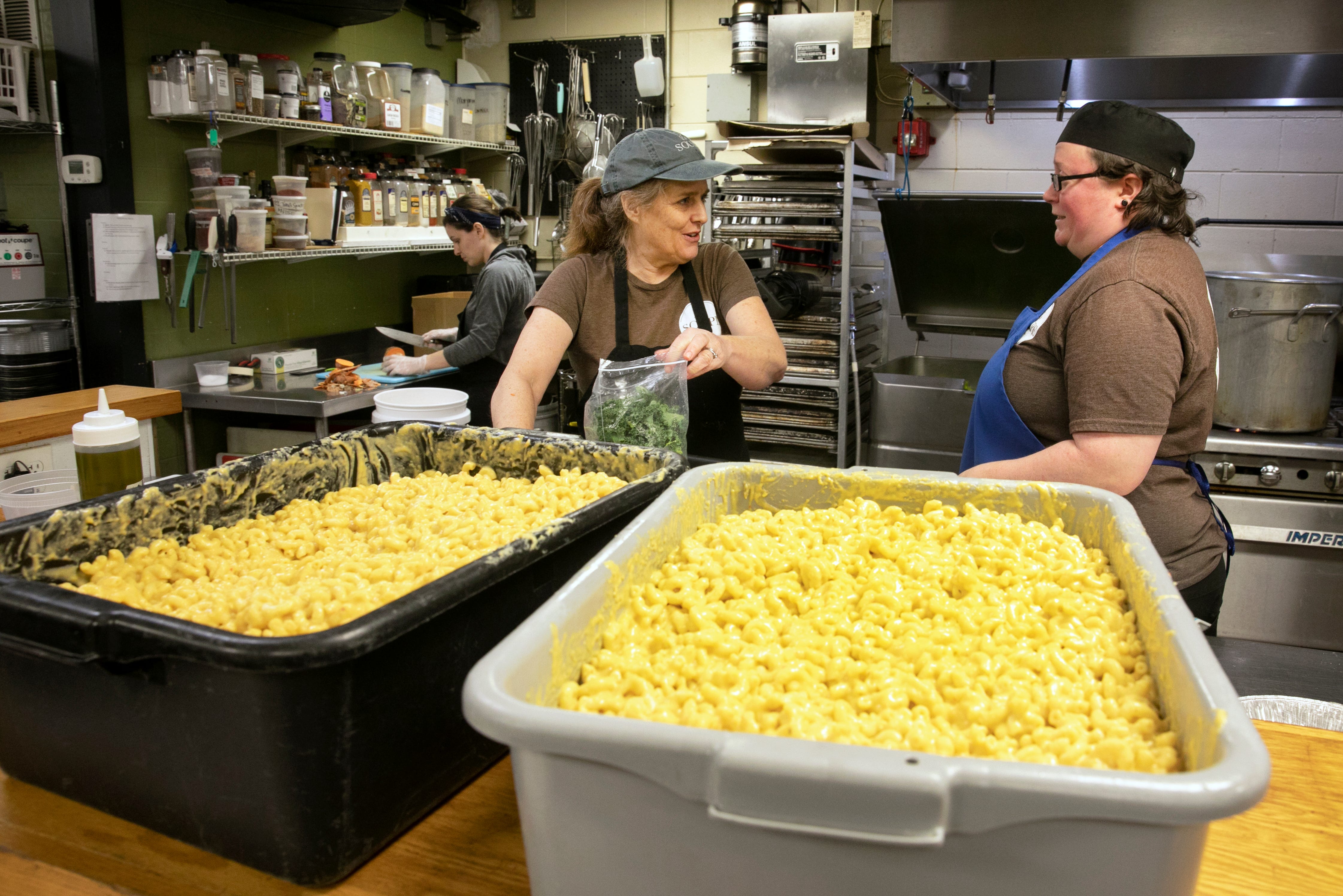 Suzy DeYoung, executive director and founder of La Soupe, center, works with head chef Miranda Maszk to prepare family meals for Cincinnati Public School families, Saturday, March 14, 2020. La Soupe has been rescuing food and feeding those in need since 2014. With CPS closed due to the coronavirus, DeYoung jumped into action to create the meals that include mac and cheese, broccoli and prime rib and au jus, along with a chimichurri sauce. They are also offering turkey and chicken as a protein. 