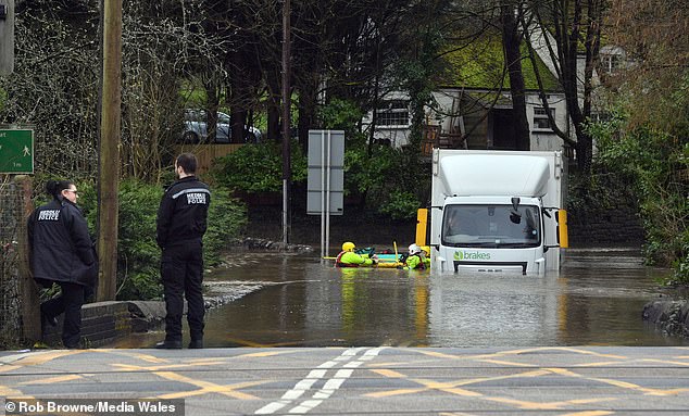 This is the moment a lorry driver was rescued from his cab when his lorry got stuck on a flooded road today