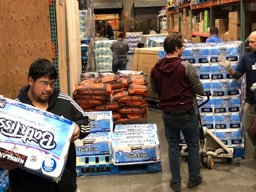 Shoppers rush to pick up toilet paper that had just arrived at a Costco store on Saturday in Tacoma, Wash. Within minutes, several pallets of toilet paper and paper towels were sold out as people continue to stock up on necessities due to fear of the COVID-19 coronavirus. (Ted S. Warren/AP)
