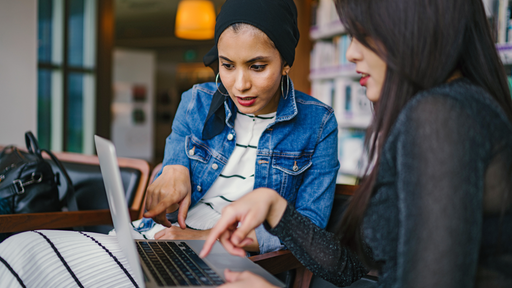 Two Women Looking And Pointing At Macbook Laptop 1569076