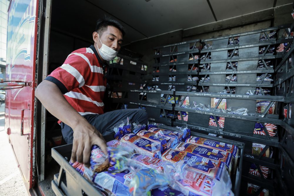 A Gardenia staff unloads fresh loaves of bread at a convenience store in Petaling Jaya March 25, 2020. — Picture by Ahmad Zamzahuri