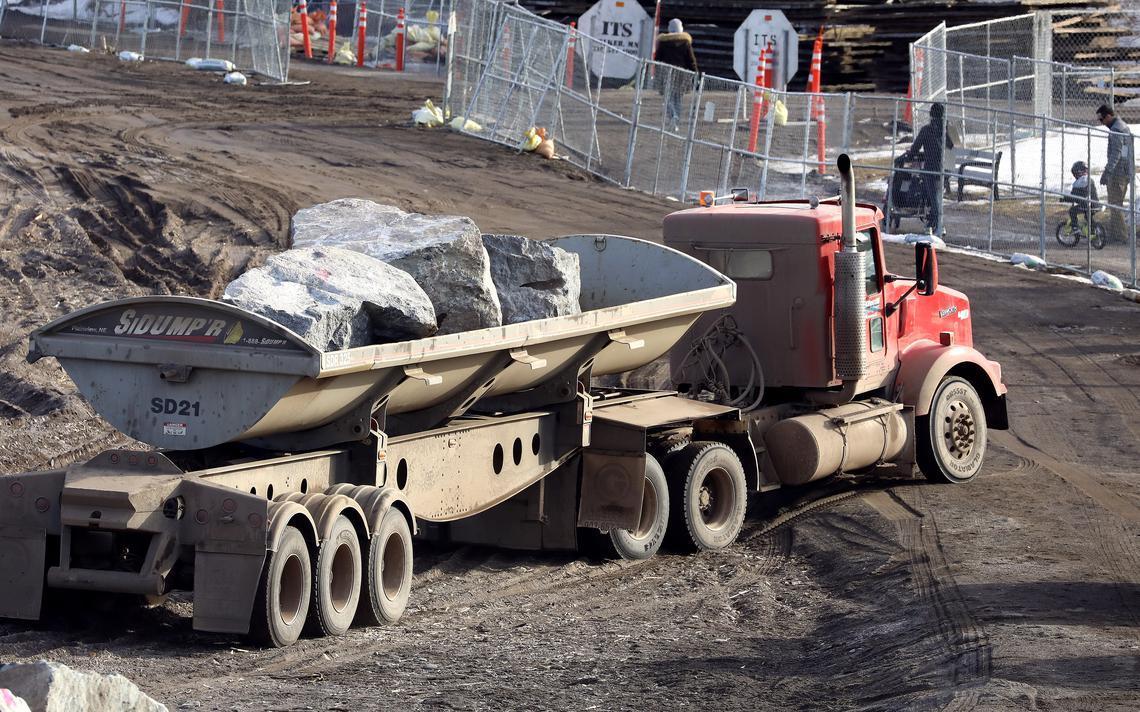 A side dump truck backs into position to be unloaded on the Canal Park beach Wednesday while pedestrians walk on the detoured Lakewalk just outside the fenced construction zone. (Steve Kuchera / skuchera@duluthnews.com)