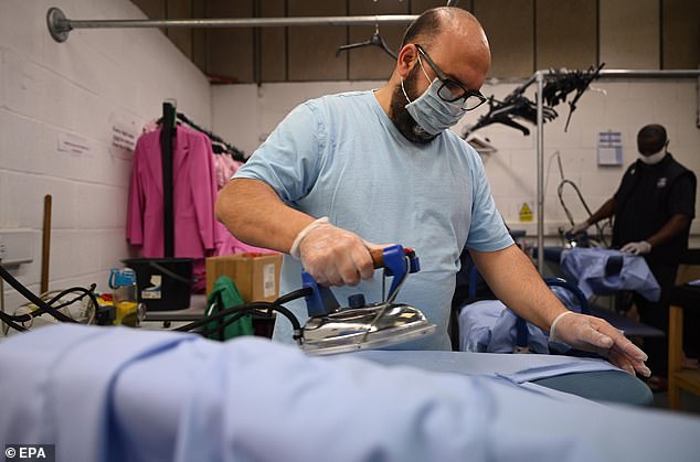 A member of staff at the Fashion Enter factory irons medical scrubs as clothes manufacturers try to produce more personal protective equipment