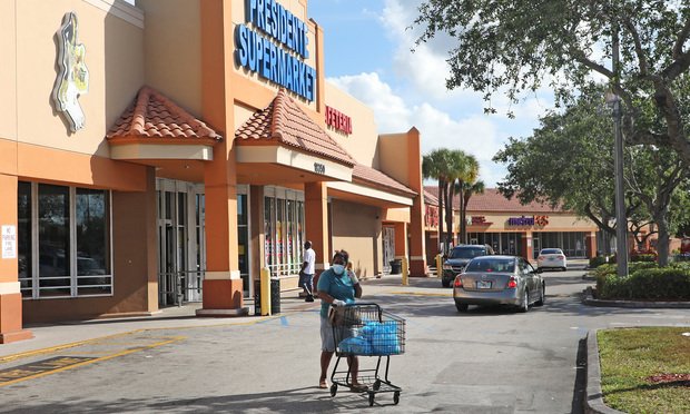A shopper, wearing a protective mask for COViD-19, walks out of Presidente Supermarket at 18350 NW 7th Ave at Miami Gardens Shopping Center.