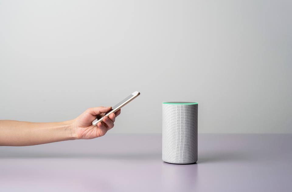 Woman using a Smart speaker with smart phone.