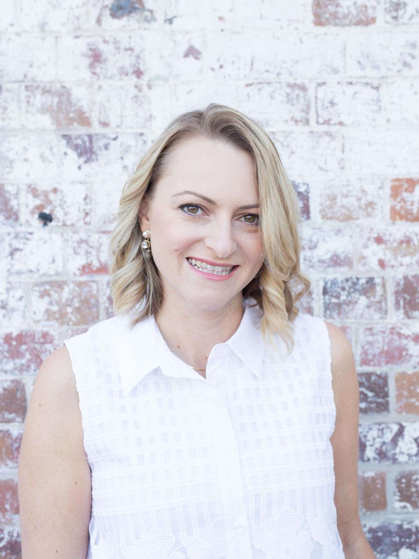 A woman stands in front of a brick wall