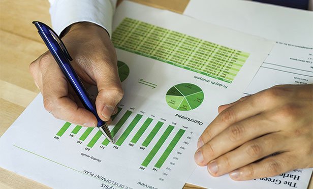 Businessman with pen and green charts