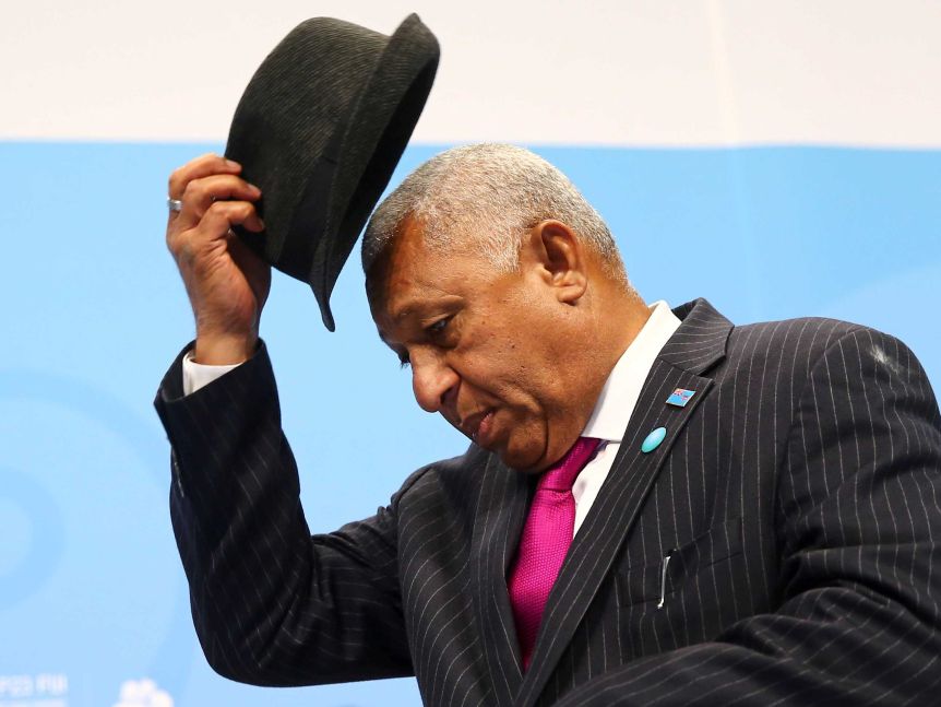 Frank Bainimarama takes off his hat.