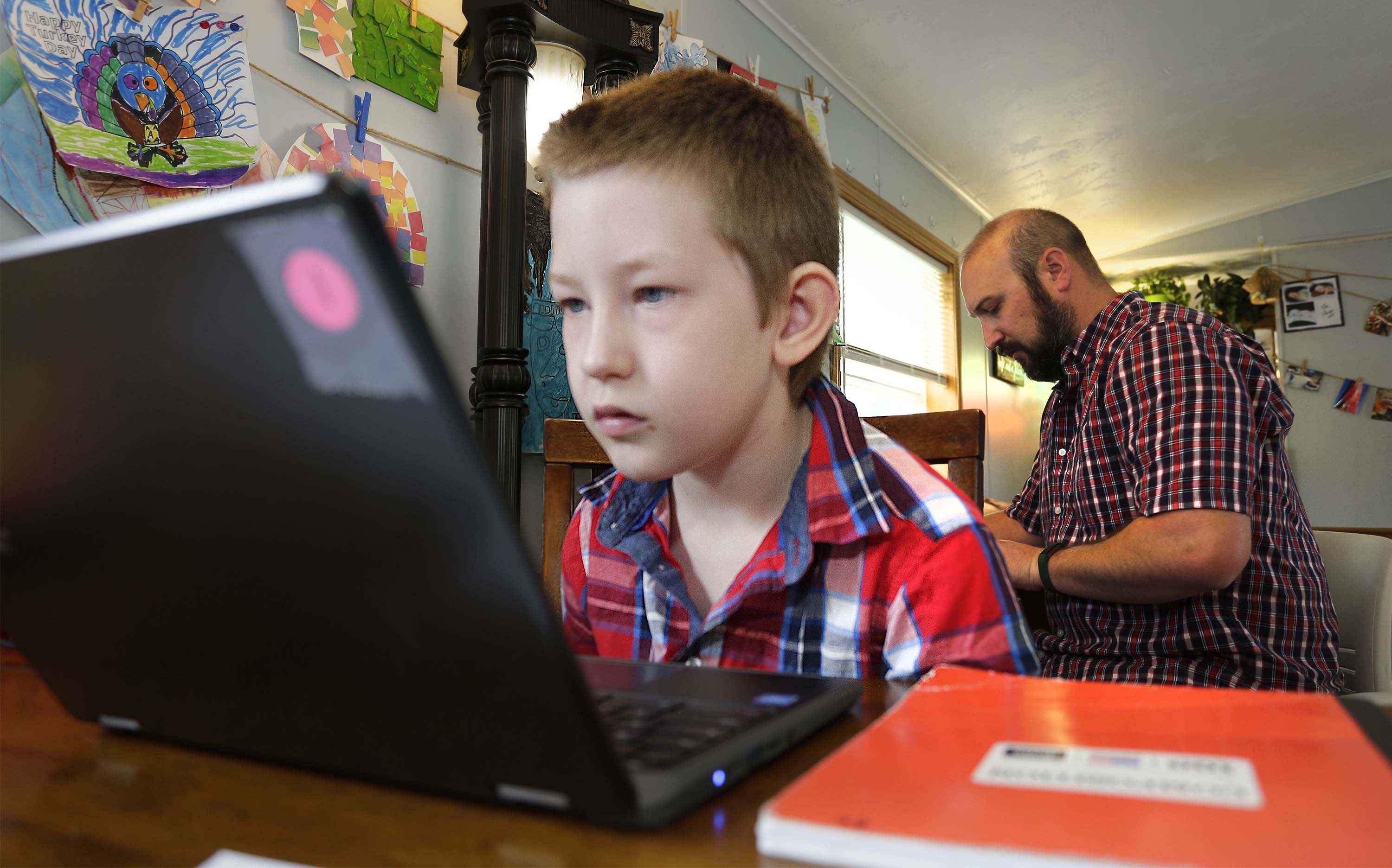 Eli Bartell, 8, leans closer to examine his screen, while his dad Andy works remotely last week at their home in Sheboygan.