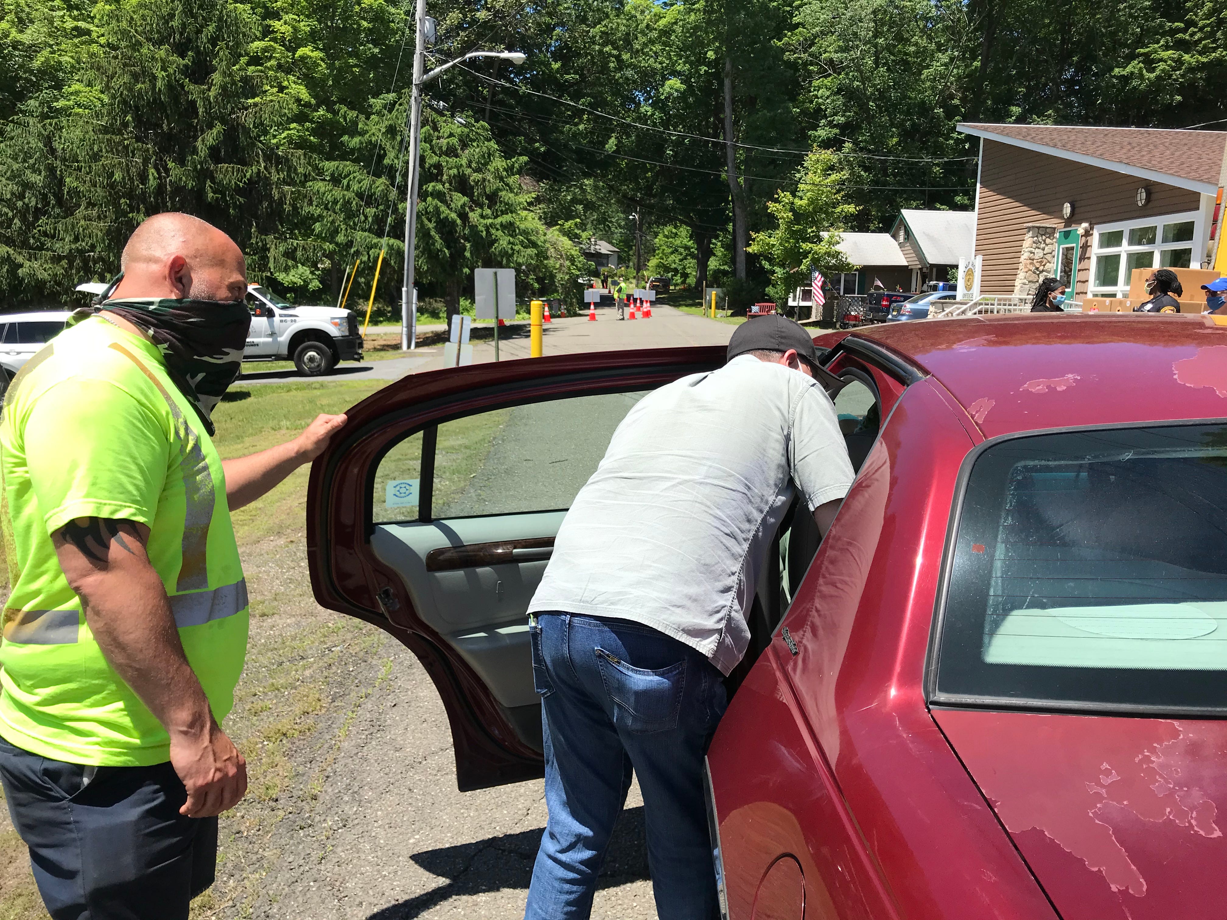 Workers placing a food package in a car at Camp Hope on Monday.