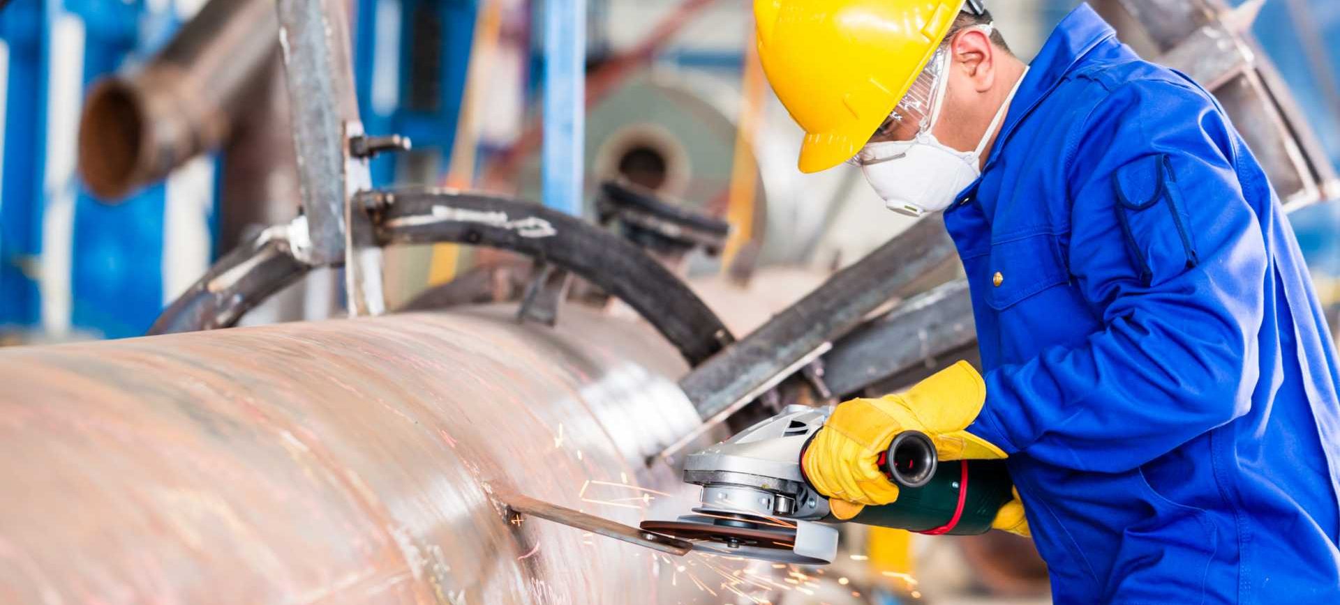Industrial worker in manufacturing plant grinding to finish a pipeline - shutterstock_454261678 (1)