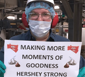 Worker holding sign: Making more moments of goodness Hershey strong