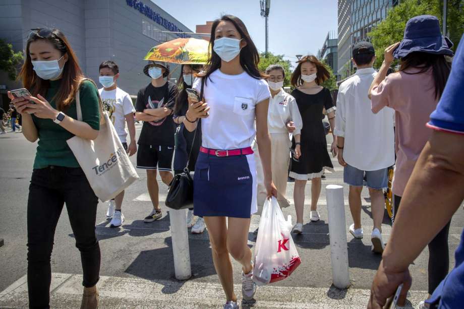 People wear face masks to protect against the coronavirus as they walk across an intersection in Beijing, Friday, June 5, 2020. China on Friday reported five new confirmed coronavirus cases, all of them brought by Chinese citizens from outside the country. Photo: Mark Schiefelbein, AP / Copyright 2020 The Associated Press. All rights reserved