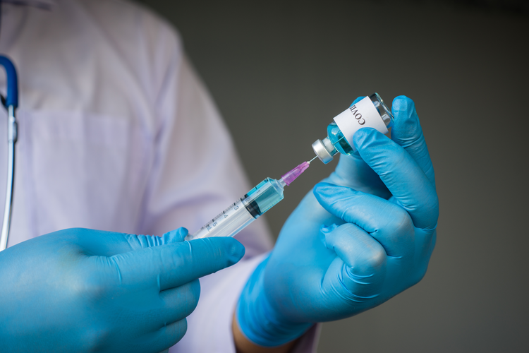 Gloved hands putting needle into a glass vial