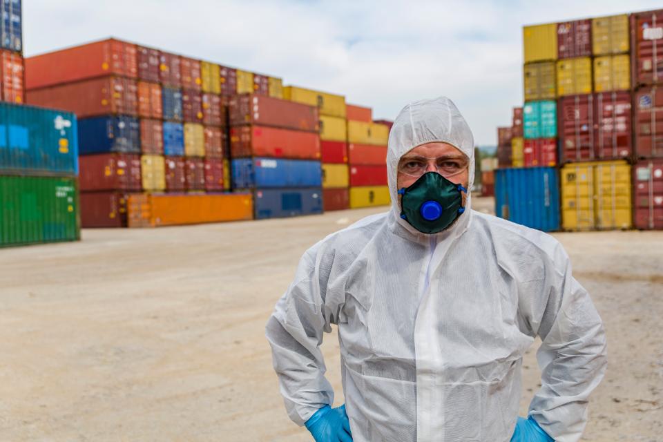 Worker in protective suit and Containers box from Cargo freight ship for import export