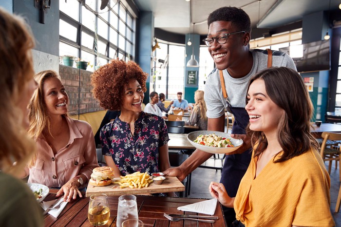 Group of friends being served by a waiter.