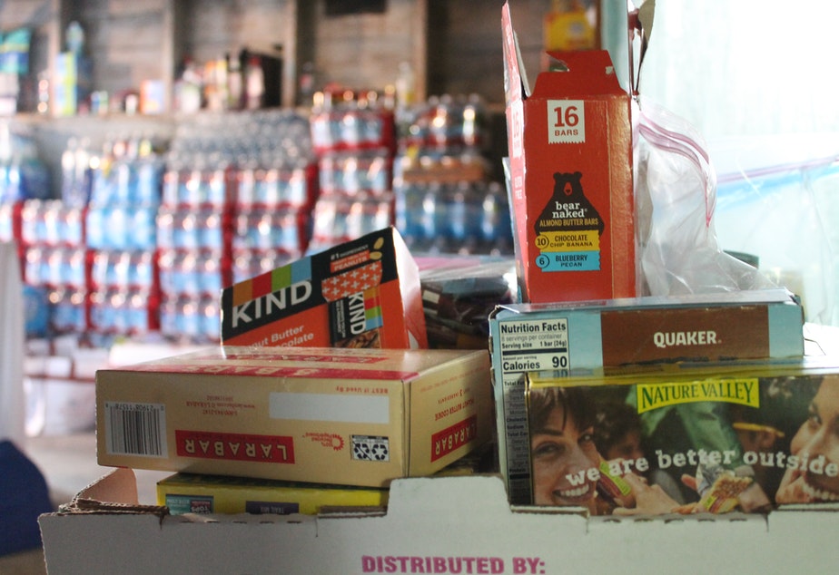 caption: Stacks of protein bars feed protesters on the front lines. Behind them, a wall of water bottles. July 1, 2020. 