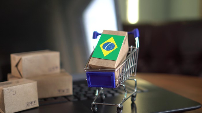 Small boxes with a Brazilian flag and a shopping cart on a laptop keyboard.