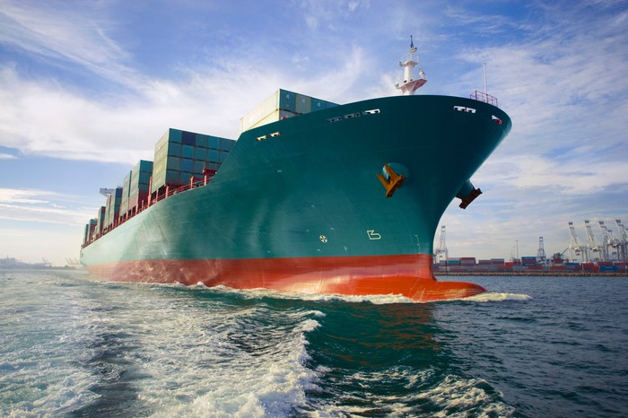 A loaded cargo ship sails out of port.