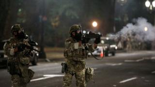 A federal law enforcement official fires tear gas at protesters during a protest against racial inequality in Portland, Oregon