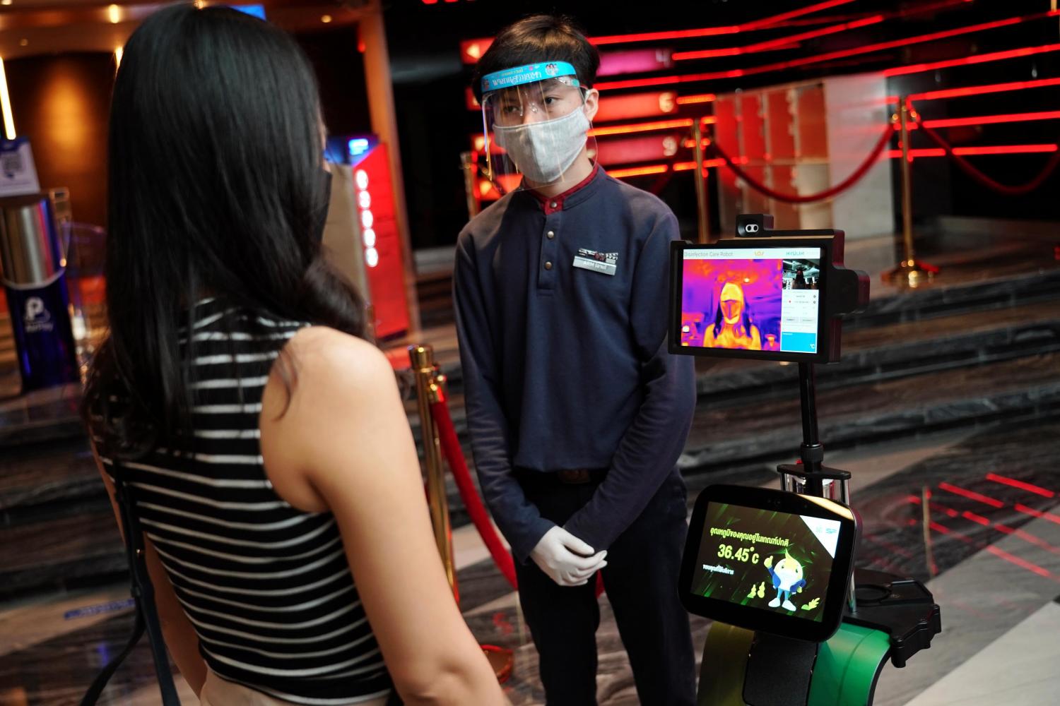 A robot is used to check a customer's temperature at the entrance of a cinema.
