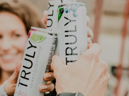 Smiling woman holding can of Truly hard seltzer.