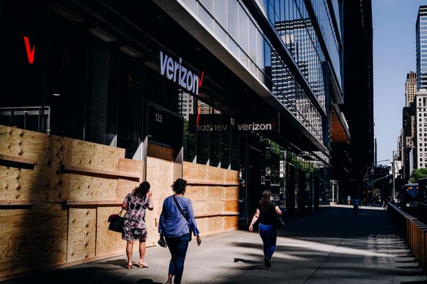 Pedestrians pass a boarded up Verizon store in Times Square New York, U.S., on Tuesday,...