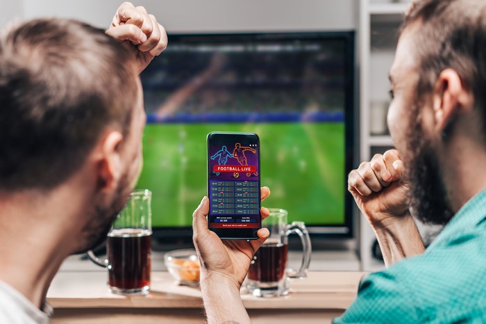 Two people betting on sports on a mobile phone.