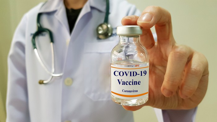 A physician holds a bottle labeled COVID-19 vaccine