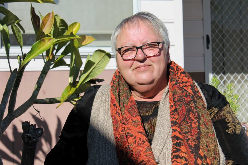 Pam Parker, sat in her backyard, smiles at the camera. 