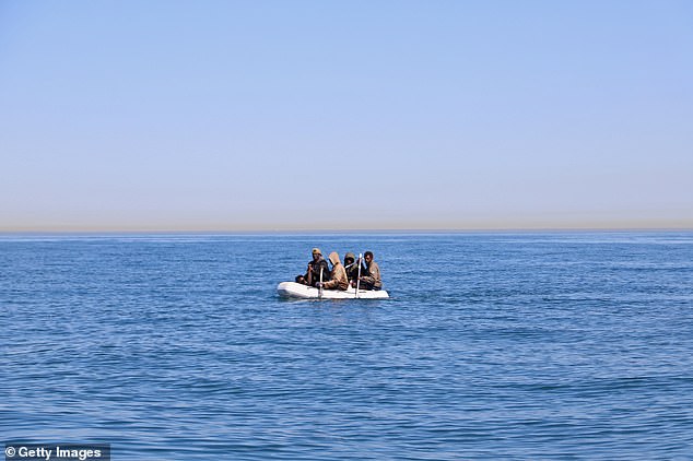 Four men, some using shovels as paddles, use a small dinghy to cross the English Channel on August 7
